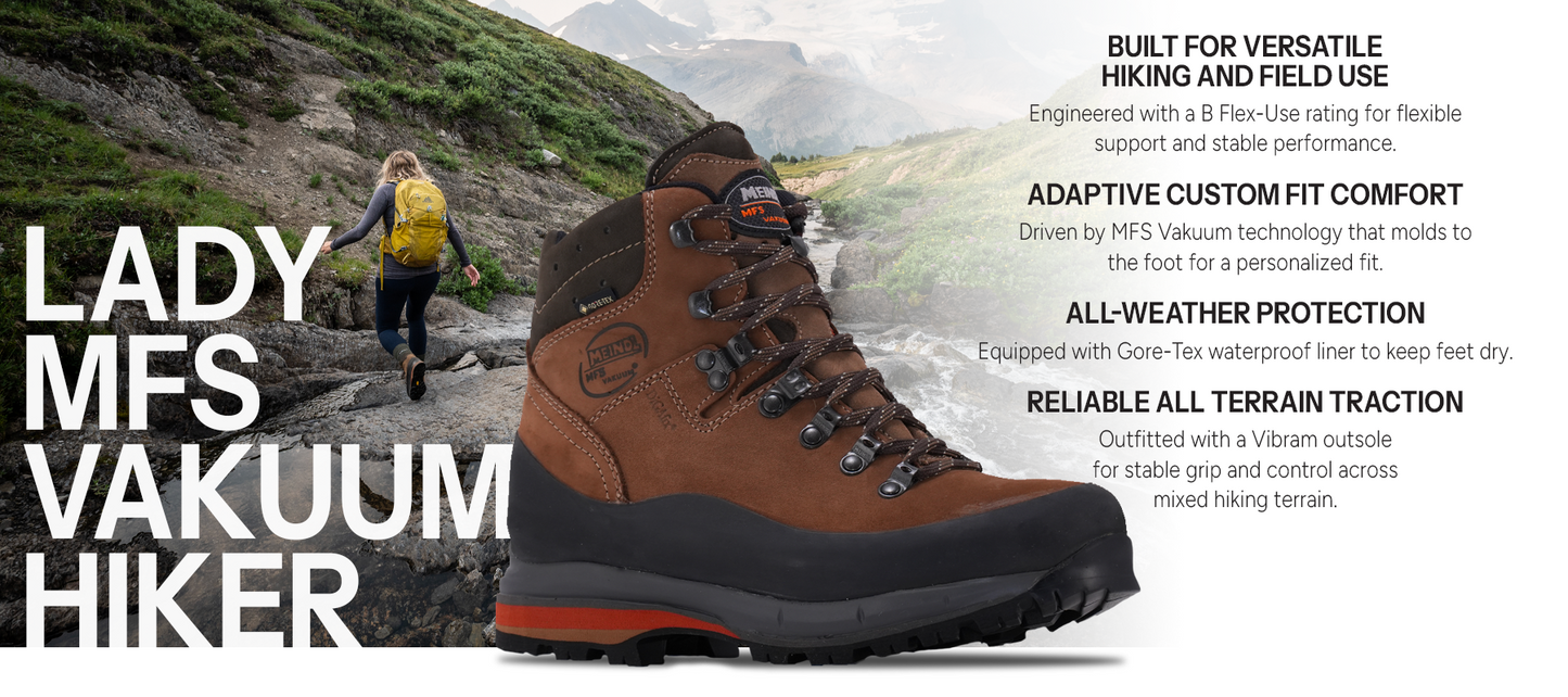 Meindl Lady MFS Vakuum Hiker – Brown Full-Grain Leather Women's Gore-Tex Hiking Boot on Alpine Rocky Terrain With Female Hiker in Background – Features: Built for Versatile Hiking and Field Use With B Flex-Use Rating, Adaptive Custom Fit With MFS Vakuum Memory Foam Technology, All-Weather Protection With Gore-Tex Waterproof Liner, Reliable All Terrain Traction With Vibram Outsole