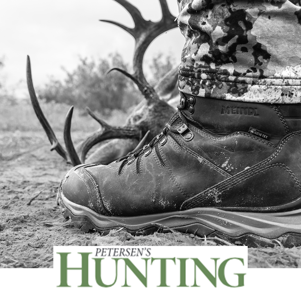 Meindl EuroLight Hunter Uninsulated – As Featured in Petersen's Hunting Magazine – Lightweight Gore-Tex Hunting Boot With Meindl Badge Visible Worn by Hunter in Camouflage Beside Deer Antlers on Sandy Terrain