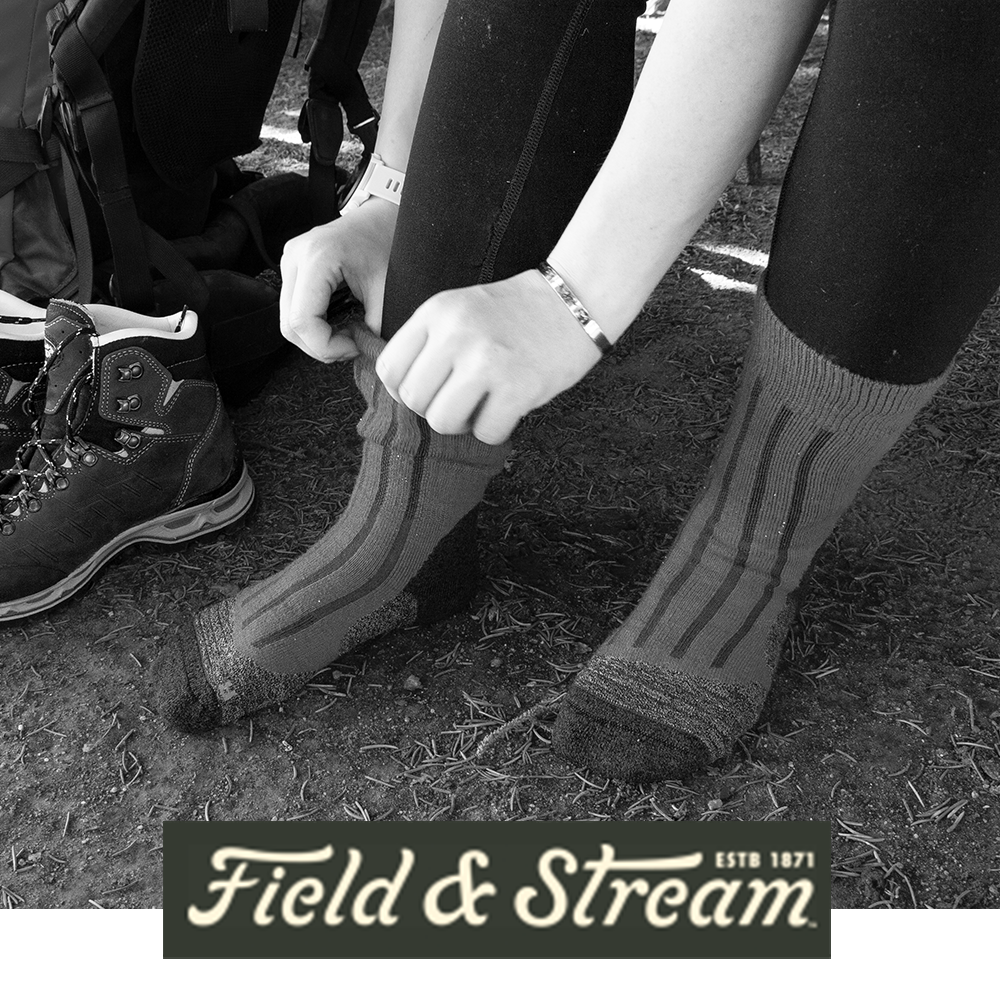 Meindl Lady MT6 Mid-Weight Merino Wool Sock – As Featured in Field and Stream Magazine – Women's Merino Wool Hiking Sock Being Pulled On by Female Hiker Seated on Trail With Hiking Boot and Backpack Visible