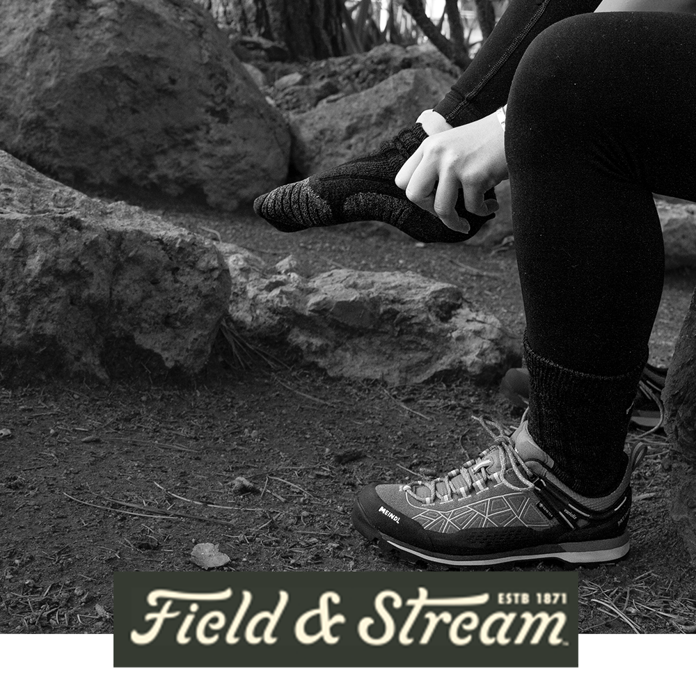 Meindl Lady MT8 Heavyweight Merino Wool Sock – As Featured in Field and Stream Magazine – Women's Heavyweight Merino Wool Hiking Sock Being Put On by Female Hiker Seated on Rocky Terrain Beside Meindl Gore-Tex Trail Shoe