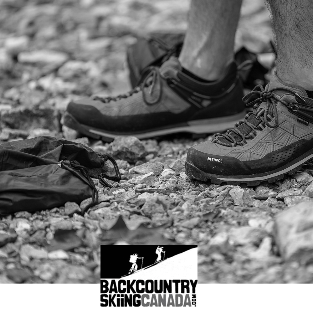 Meindl Literock Free Trail Shoe – As Featured in Backcountry Skiing Canada – Gore-Tex Lightweight Trail Shoe Worn by Hiker on Rocky Gravel Terrain Beside Dry Bag With Meindl Badge and Gore-Tex Label Visible