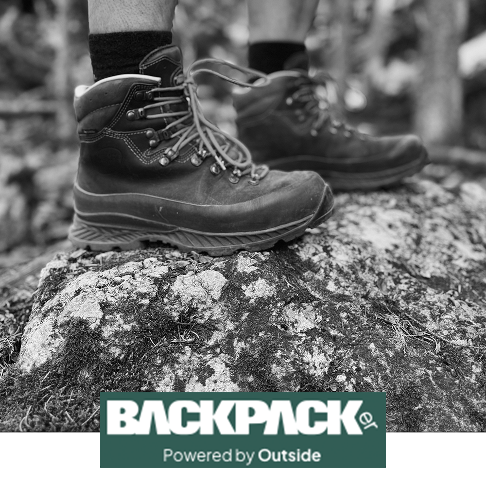 Meindl MFS Bergell Hiker – As Featured in Backpacker Magazine Powered by Outside – MFS Custom-Fit Leather Hiking Boot Worn by Hiker Standing on Lichen-Covered Rock in Forest Setting With Backpack Visible