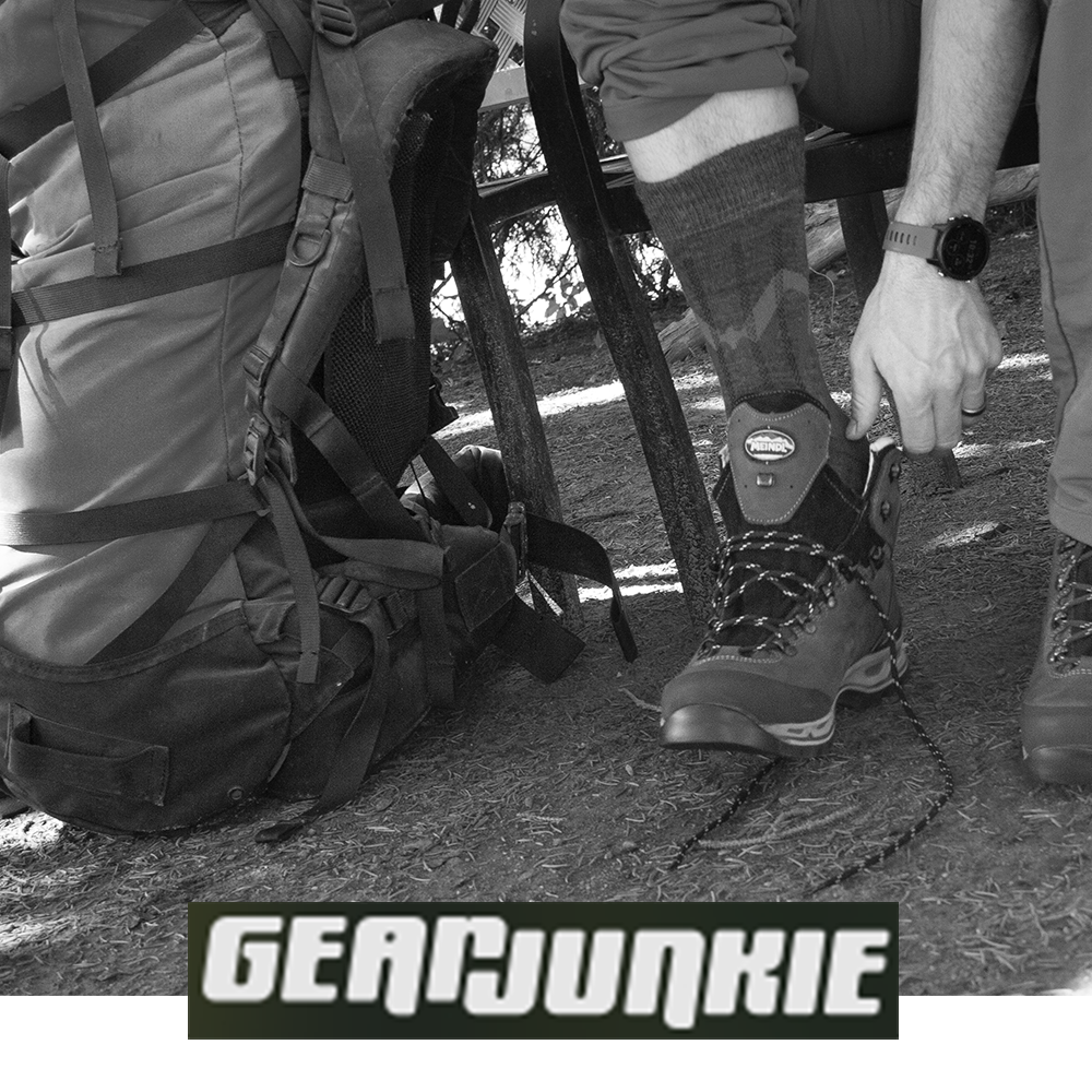 Meindl MT3.5 Merino Wool Sock – As Featured in Gear Junkie – Mid-Weight Merino Wool Hiking Sock Worn by Hiker Lacing Up Meindl Boot Beside Large Backpack in Outdoor Setting