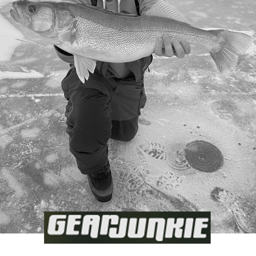 Meindl Nordkap Pro GTX Winter Boot – As Featured in Gear Junkie – Gore-Tex Insulated Winter Boot Worn by Ice Angler Kneeling on Frozen Lake Holding Large Walleye With Ice Fishing Hole Visible in Background